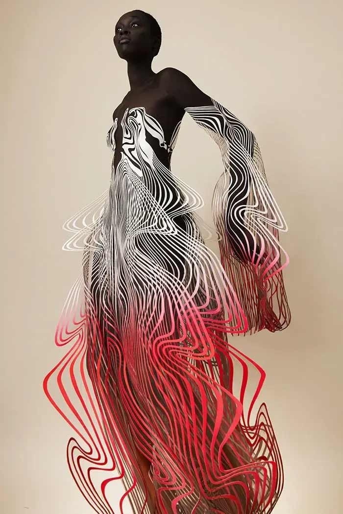 Mulher com um vestido composto por linhas vermelhas e brancas desenhado por Iris van Herpen