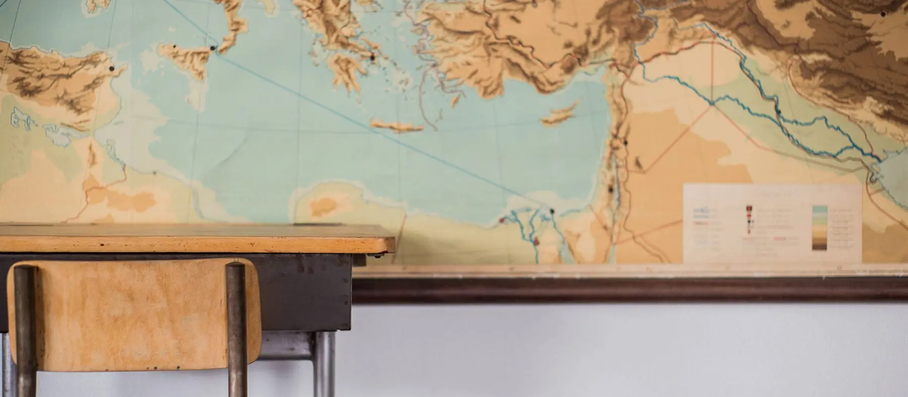 Empty desks at school classroom with world map