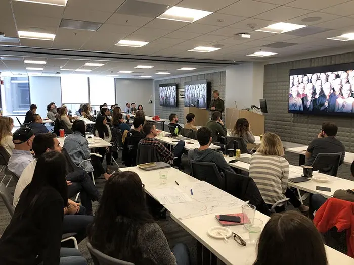 A crowd of 50 designers watches trainer Johan Verstraete giving a presentation