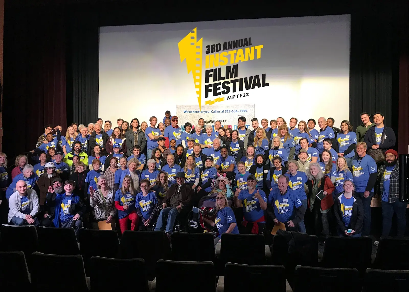 Group of seniors and students on front of movie screen at the 3rd annual Instant Film Festival. 