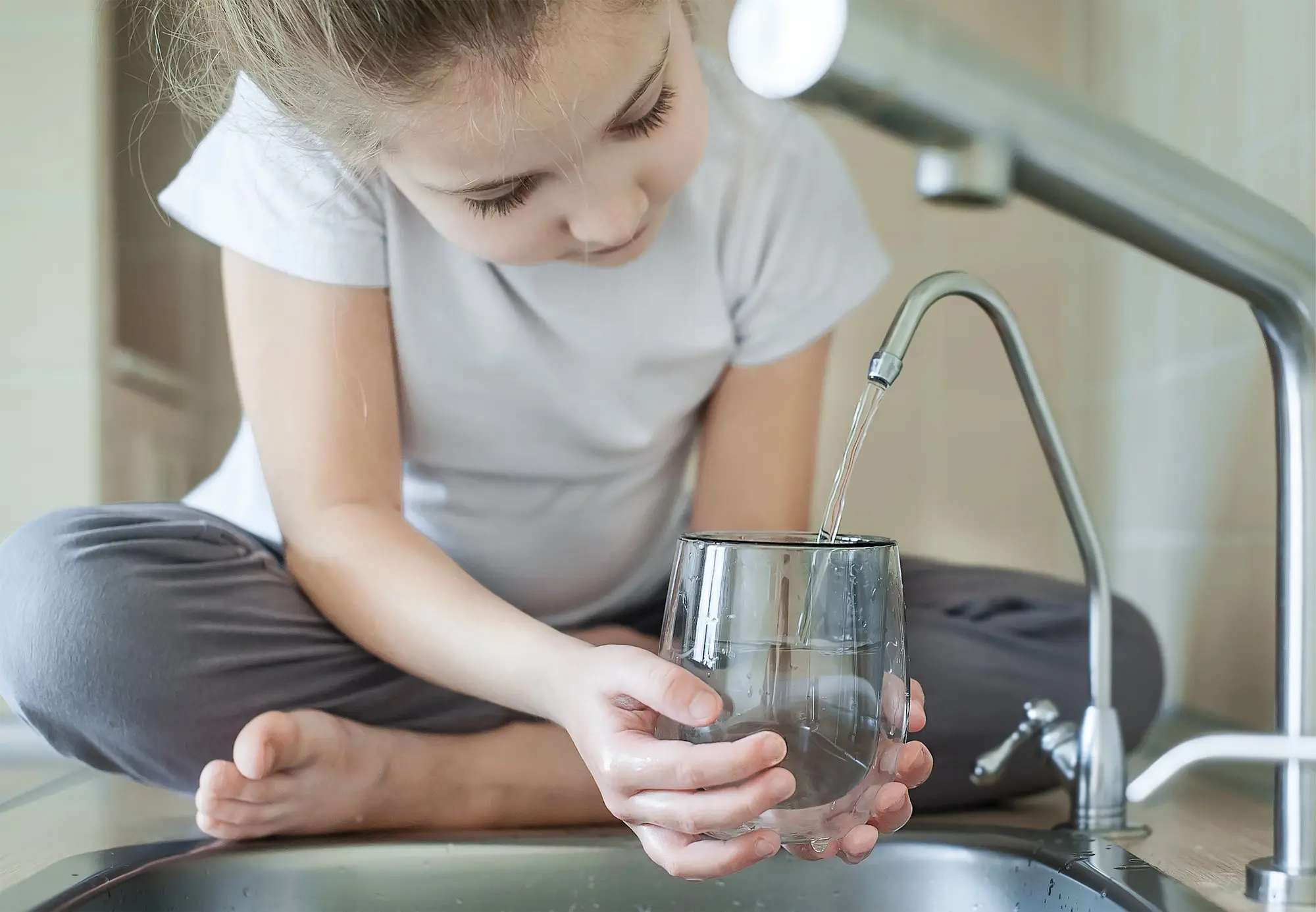 Young girl filling glass of water