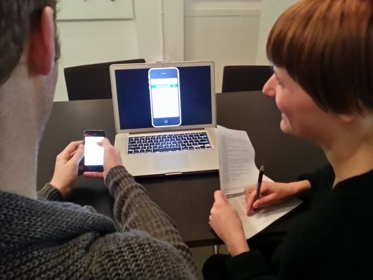 Two people laughing while working together at a computer.