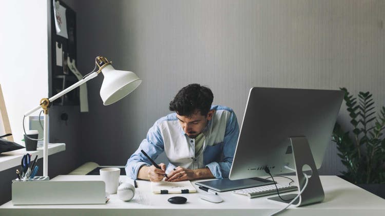 A man sits at his desk and focuses on his work.