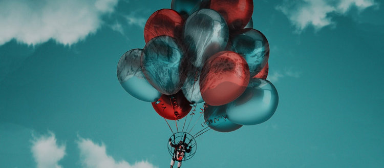 Person in air attached to balloons.
