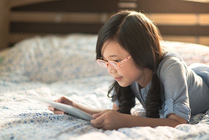 Young girl reading a tablet on the floor.