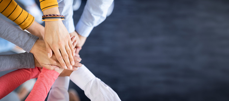 Image of a stack of hands showing unity and teamwork.