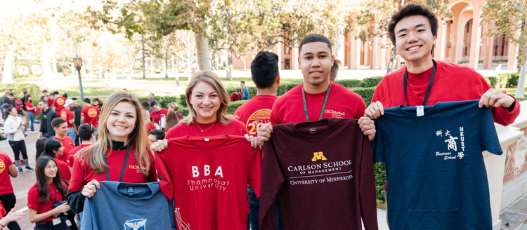 Image of university students holding a shirt representing their university.