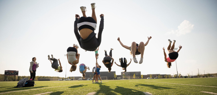 Teenage girl high school cheerleaders practicing back flip