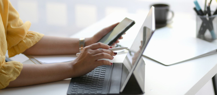 Side view of female entrepreneur focusing on her work with mock-up tablet on white table