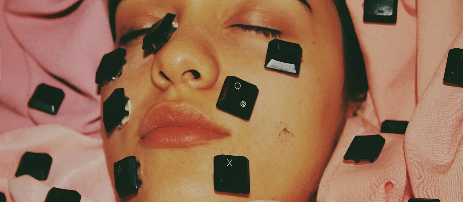 Image of woman with letters from a keyboard on her face.
