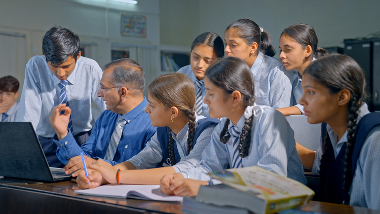 Teacher teaching students work on laptop