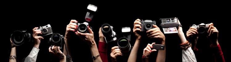 Raised hands holding different photocameras.