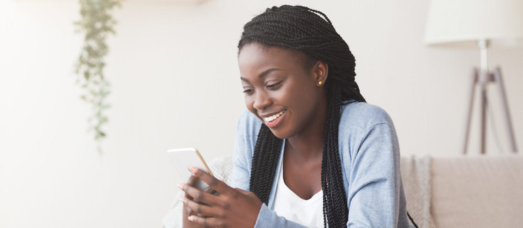 Smiling african american woman using smartphone at home