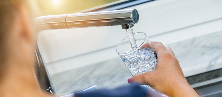 Beautiful woman filling glass with water in kitchen