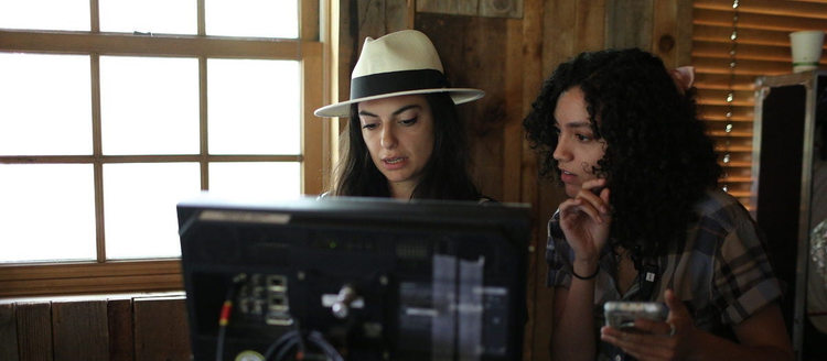 Two female directors standing behind in screen in the process of filmmaking.