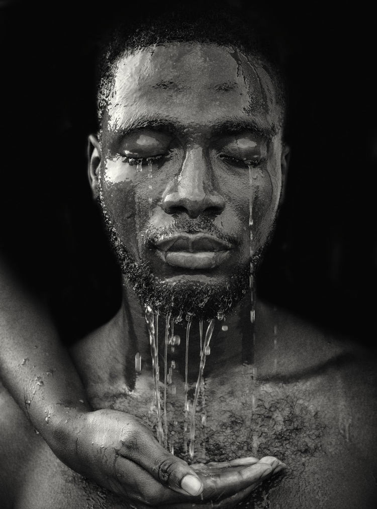Black man with water running down his face.
