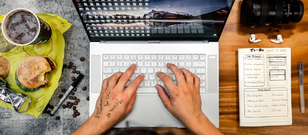 Person typing on a laptop with food next to them.
