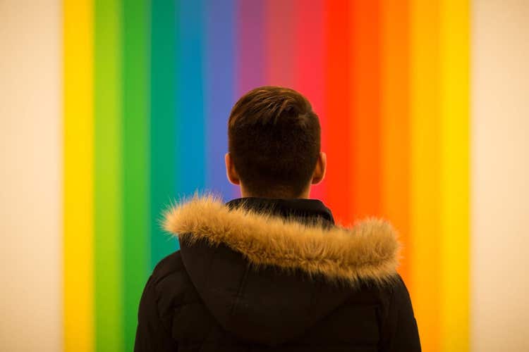 Person's back standing in front of a rainbow gradient