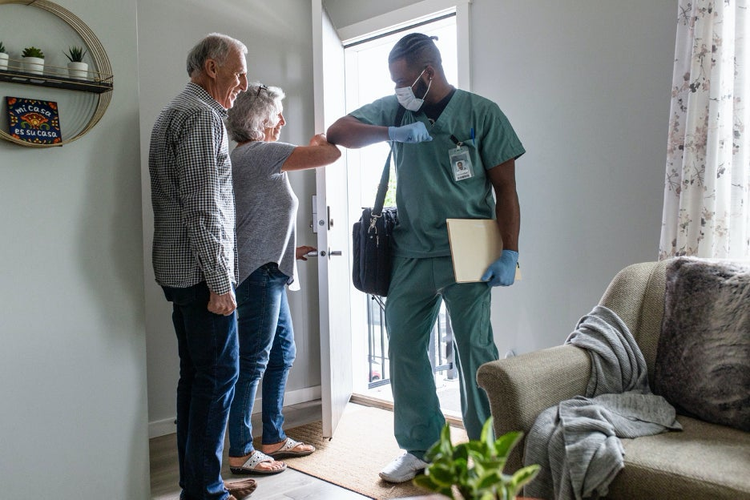 Healthcare worker touching elbows with woman