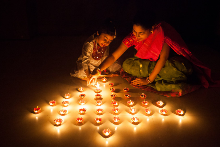 Indian woman and child lighting candles in the shape of a tree