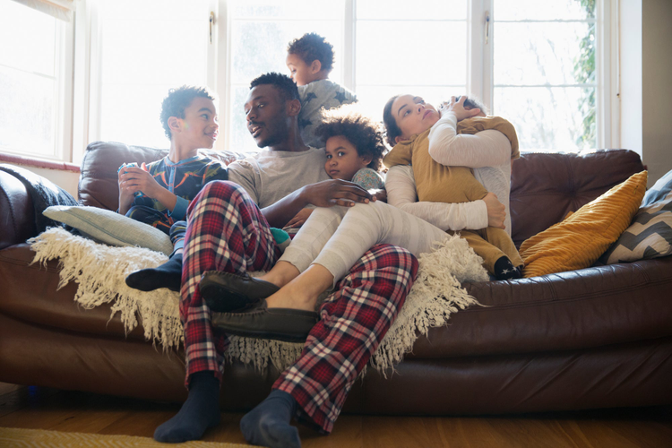 Diverse family on couch in pajamas talking and playing