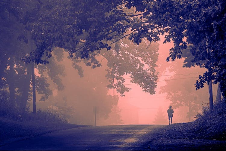 Adjusting red and blue color graded image of a person walking down a road.