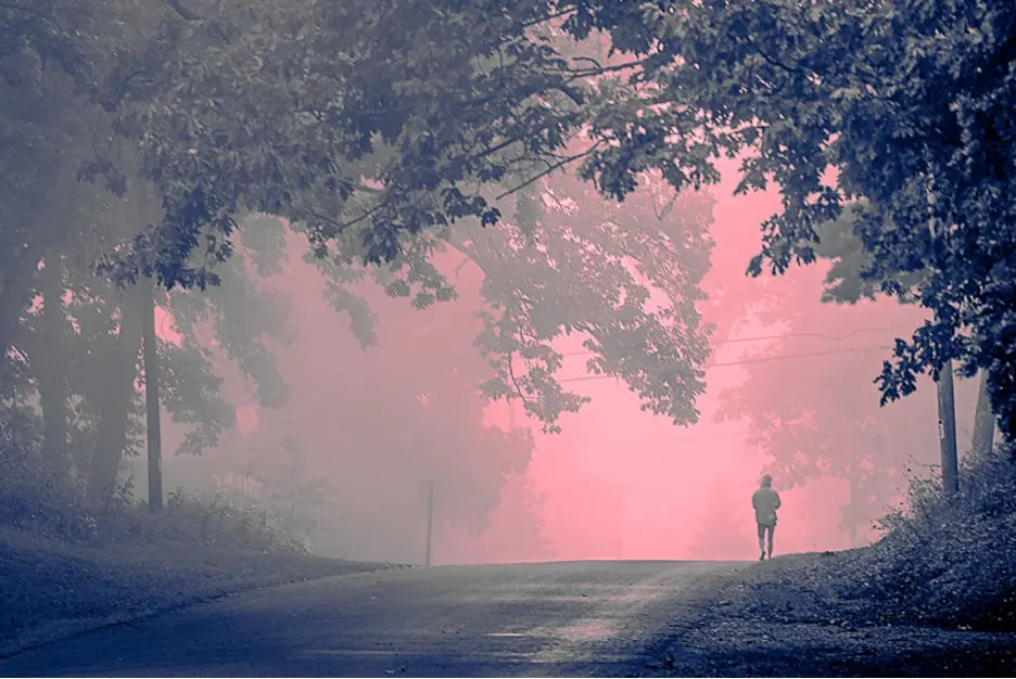 Adjusting red and blue color graded image of a person walking down a road.