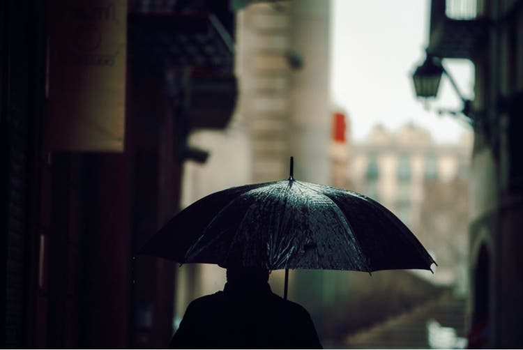 Man walking in the rain with an umbrella.