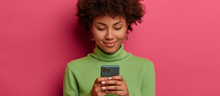 Woman smiles while looking at her cell phone.