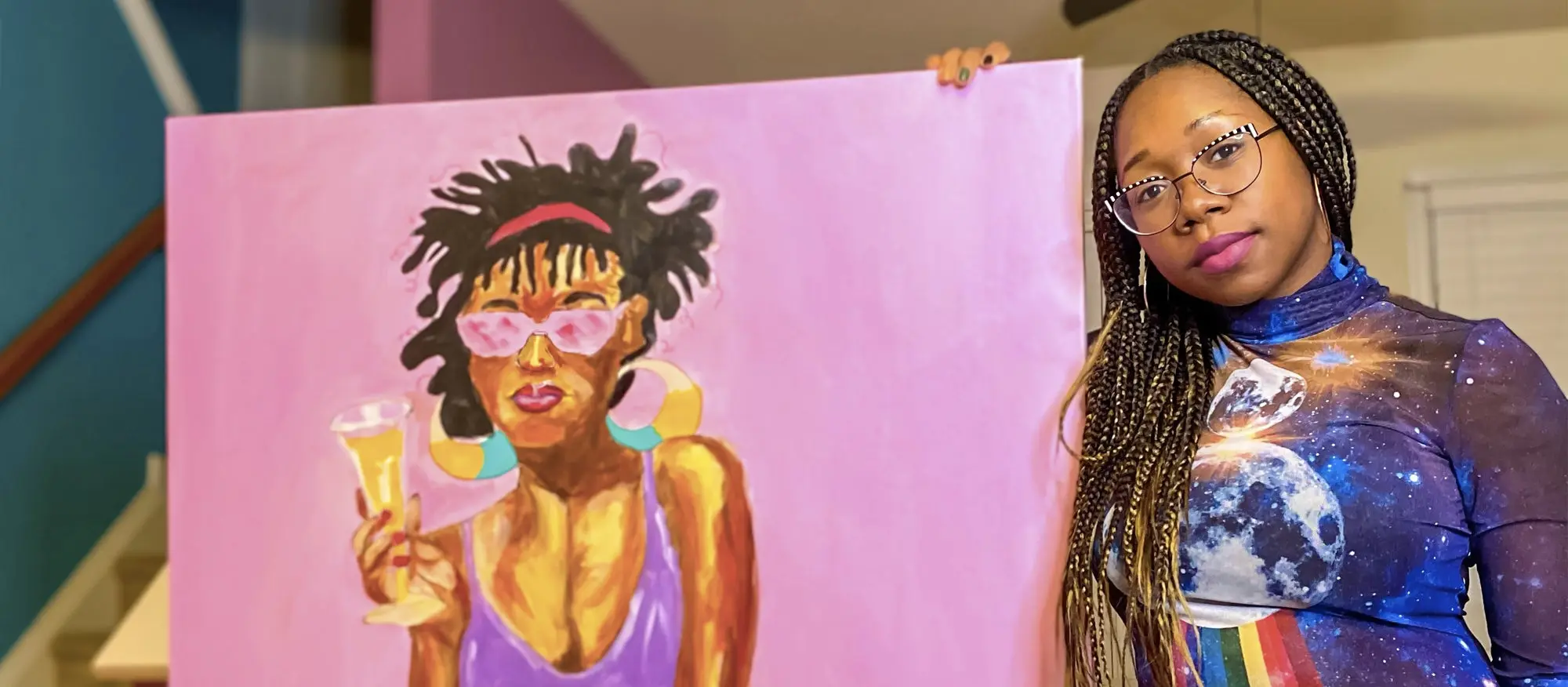 A photo of Carita, diversity & inclusion program manager at Adobe, holding one of her paintings.