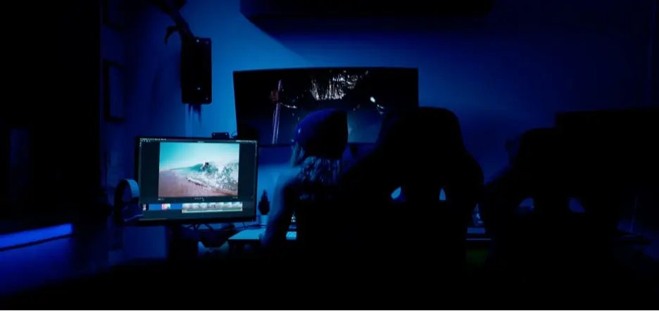 Person in dark room looking at computer screen of skim boarding photograph. 