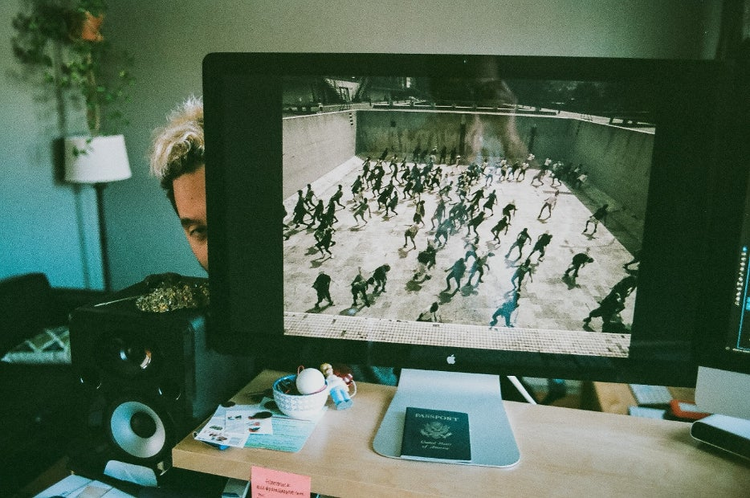 Image of computer screen with man behind it.