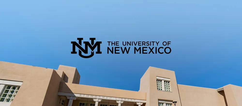 The University of New Mexico Logo against a blue sky and top of building.