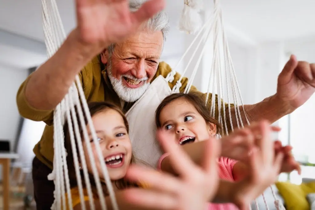 Image of older man with two young girls laughing. 