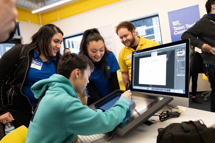 Best Buy employees watching boy experiment on computer.