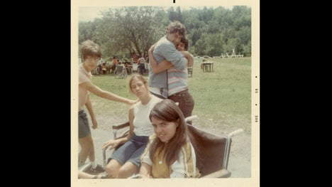 Photo of two people in wheel chairs with two people embracing behind them.