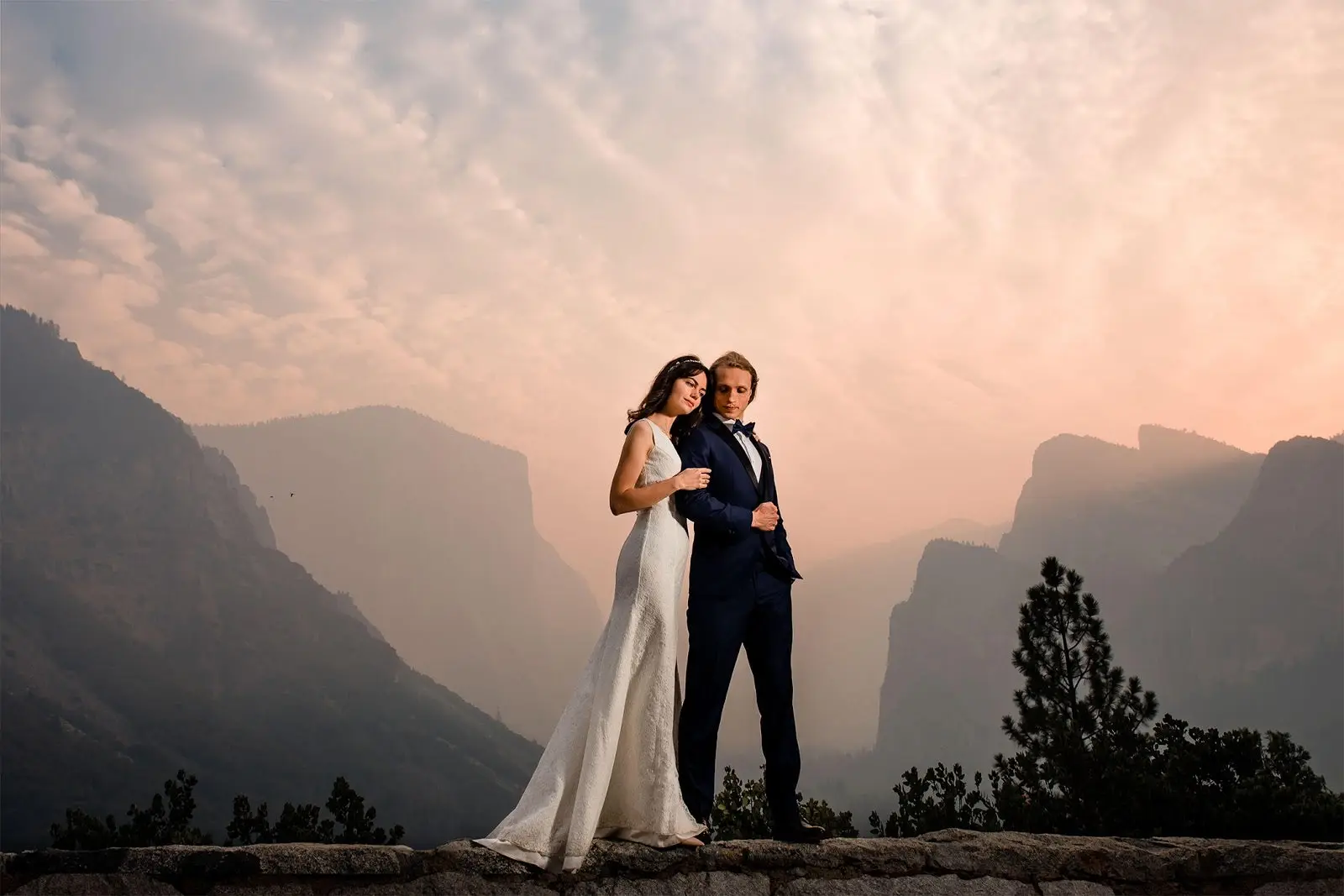 Edited version of bride and groom standing in front of mountain range. 