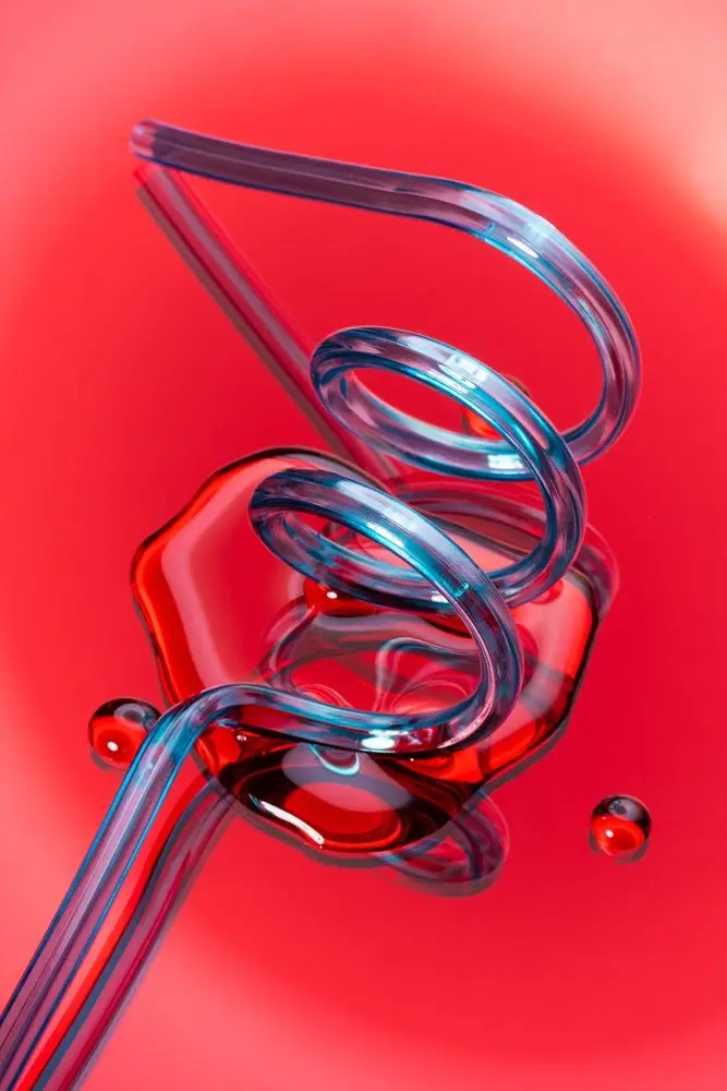 Photo of a twisty straw with spilled water on a red background.