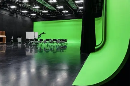 Photo of a studio with a green-screen and chairs
