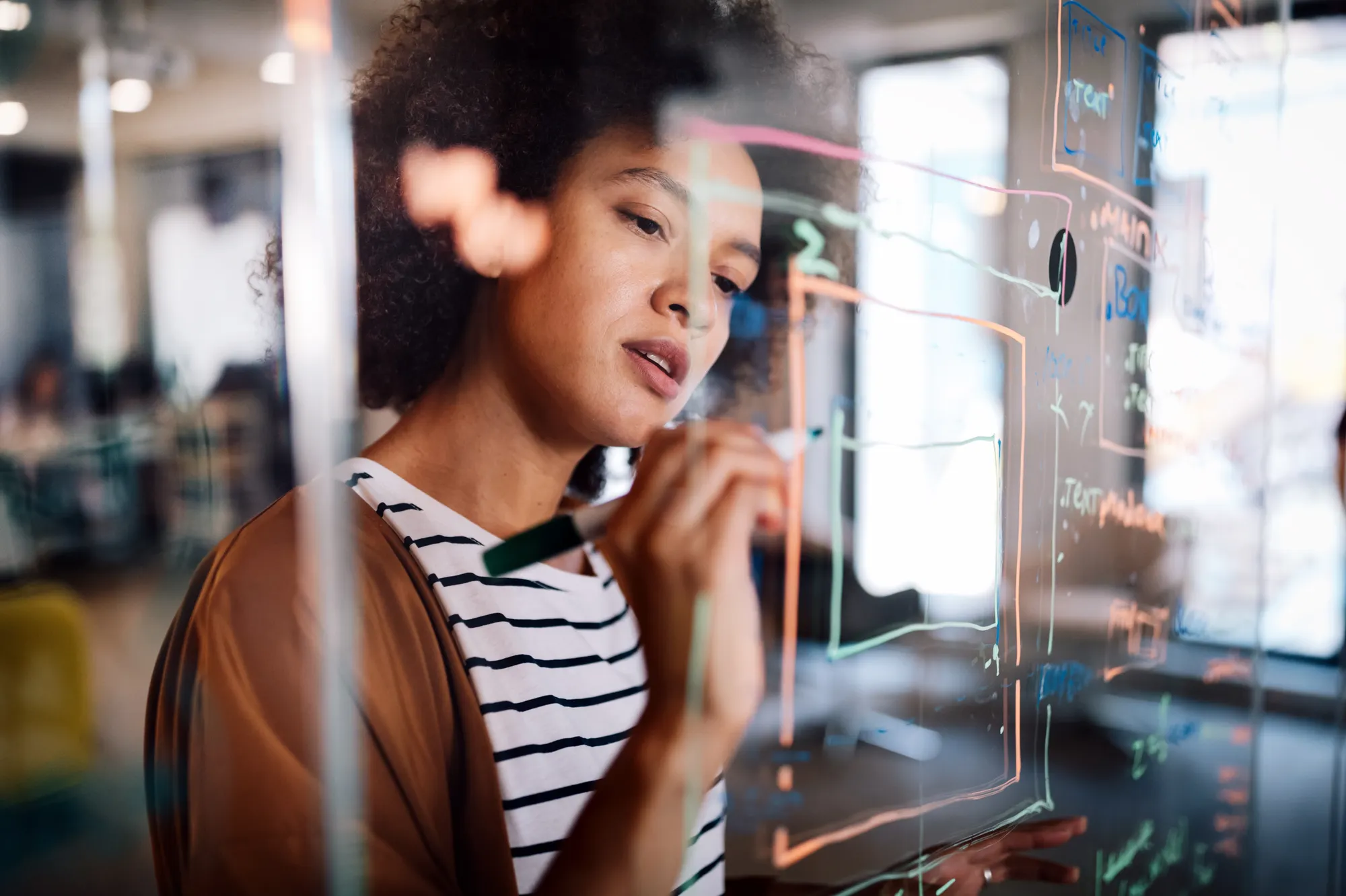 Woman writing strategy on a glass board
