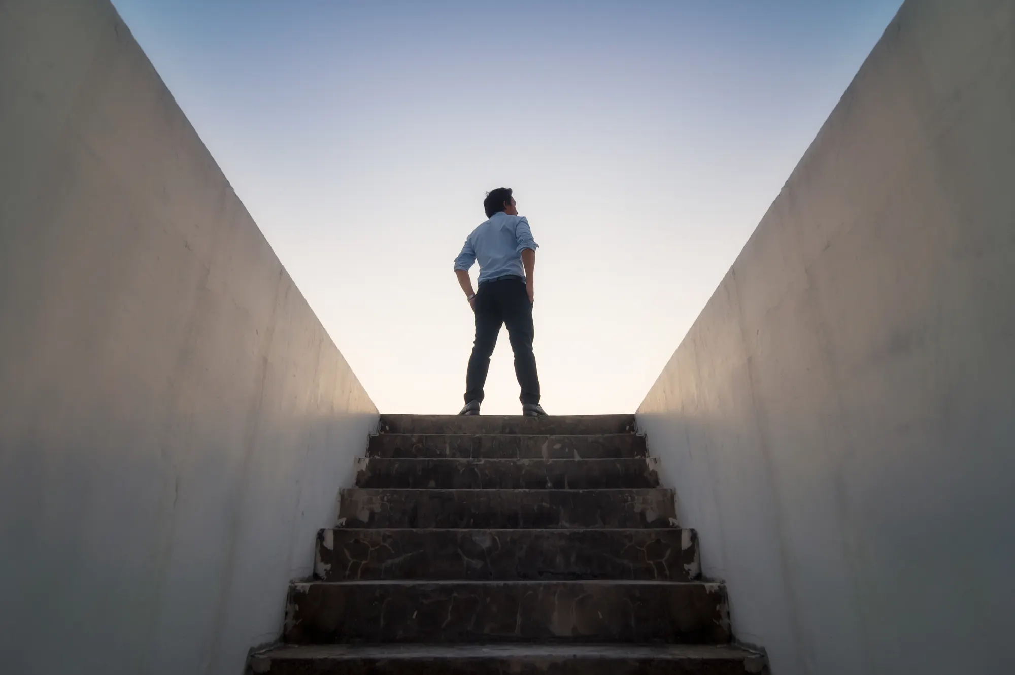 man standing at top of stairs looking towards sun