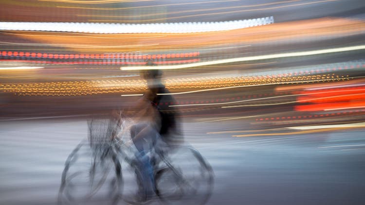 A photo of a pan-blur of someone riding a bike.