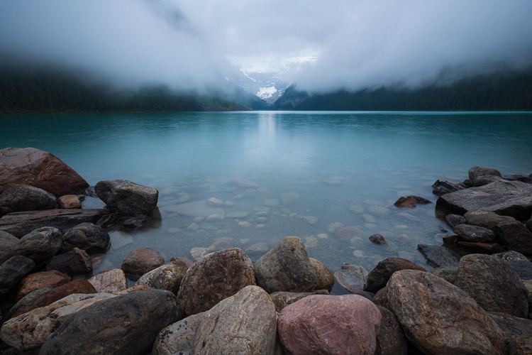 Photo shooting towards a lake with low clouds hanging over the water.