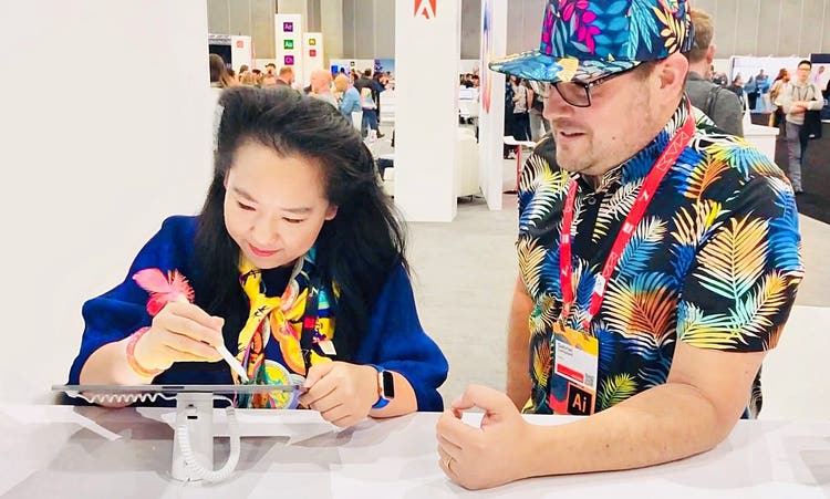 Yiying Lu drawing on an ipad with Adobe lead designer looking at her.