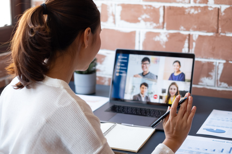 Woman at desk with laptop in video meeting