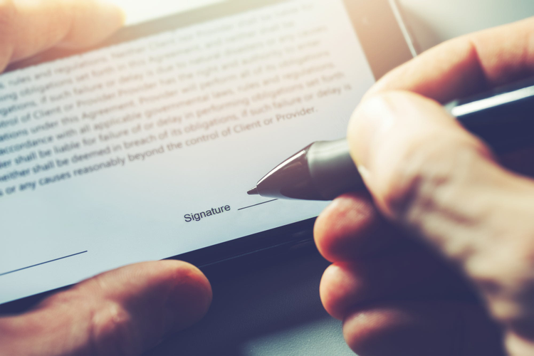 Close up photo of someone signing a document on their phone. 