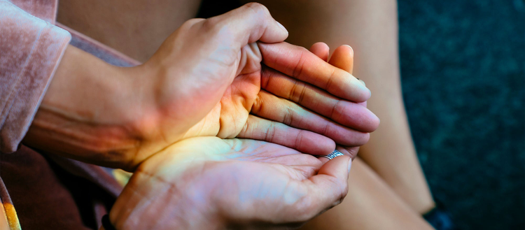 Hands cupped together with a rainbow of light shining in them. 