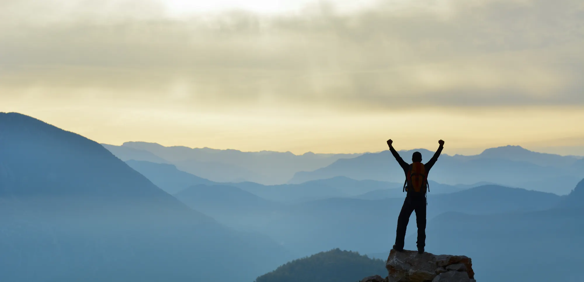 Man cheering, on top of a mountain