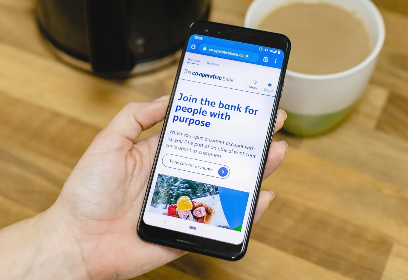Hand holding smartphone showing application page for the Co-operative bank