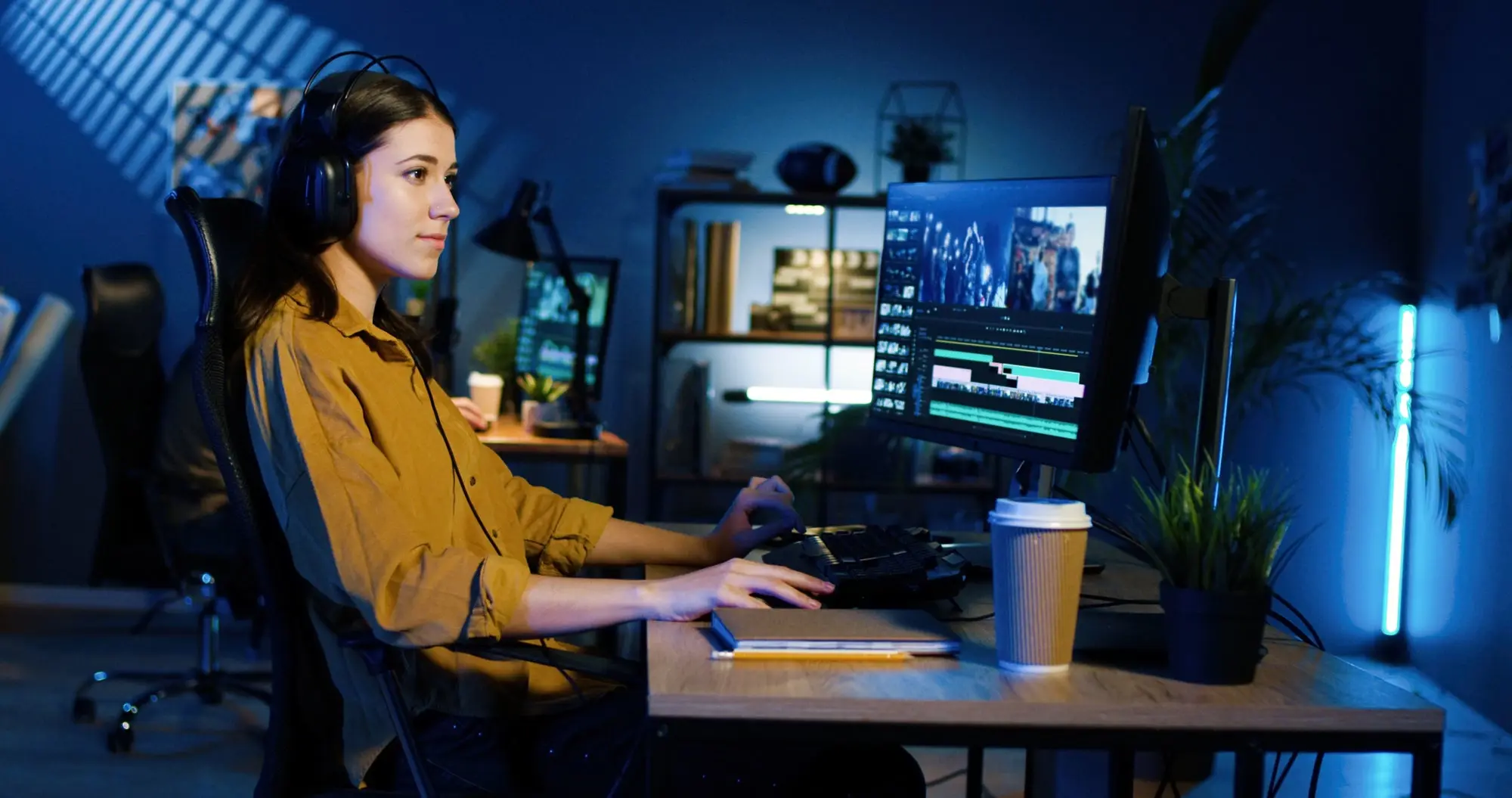 Woman sitting at computer wearing headphones.